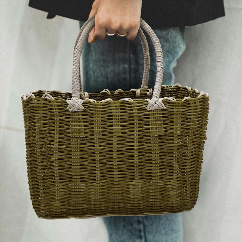 Puede incluir: Una bolsa de mano tejida de color verde y blanco con asas blancas. La bolsa tiene un borde festoneado.