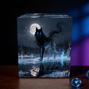May include: A cube-shaped item featuring a dark wolf with glowing blue eyes and ethereal smoke-like features, standing in a moonlit graveyard. The scene includes a full moon, water, and blue flames. Two blue dice with white numbers are on the table.