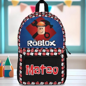 Pu&ograve; includere: Uno zaino Roblox nero e blu con un diamante rosso e un personaggio Roblox che indossa un casco. Lo zaino ha una tasca nera con il nome "Mateo" in lettere rosse.