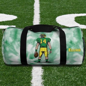 Peut inclure: Sac de sport vert et blanc avec un joueur de football américain. Le joueur porte un uniforme jaune et vert avec le numéro 14. Le nom "Elijah" est imprimé sur le côté. Poignées et sangles noires.