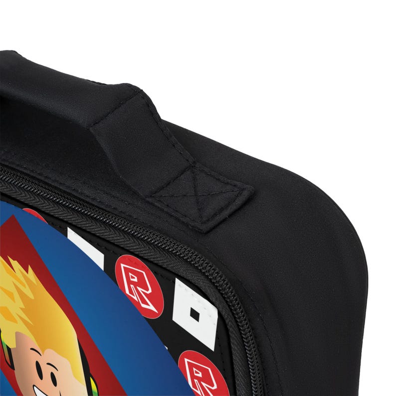 Pu&ograve; includere: Borsa da pranzo nera con chiusura a zip e manico imbottito. La borsa presenta un design colorato con un personaggio dei cartoni animati e la parola "Roblox" ripetuta ovunque.