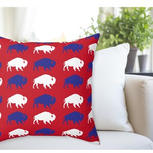 May include: Red throw pillow with a white and blue buffalo silhouette pattern.