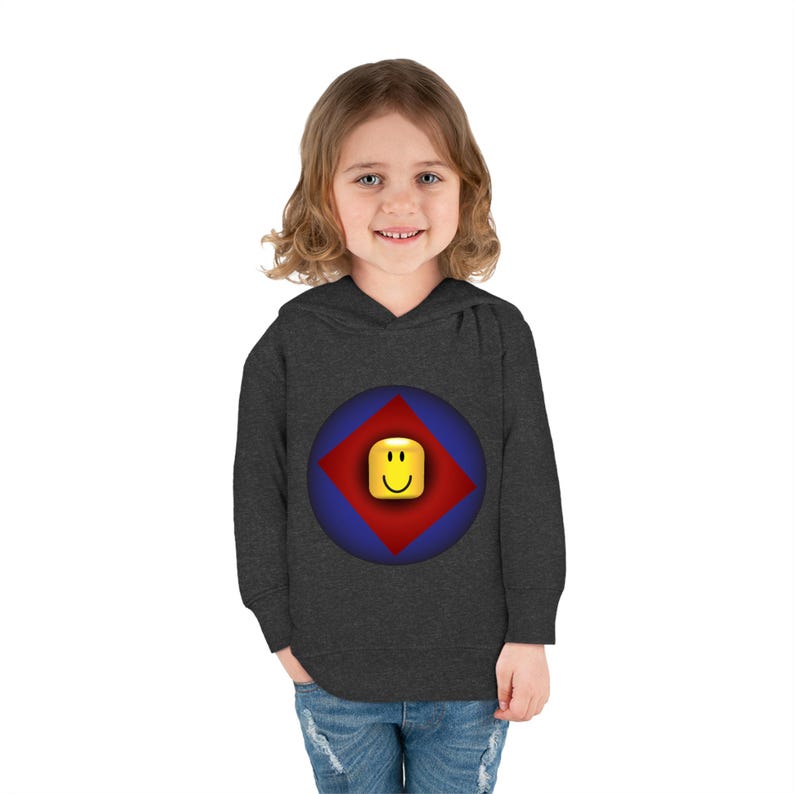 K&ouml;nnte beinhalten: Ein dunkelgrauer Kapuzenpullover mit einem blauen und roten Kreis-Motiv, das ein gelbes Smiley-Gesicht in einem roten Diamanten zeigt. Der Pullover ist f&uuml;r Kinder konzipiert.