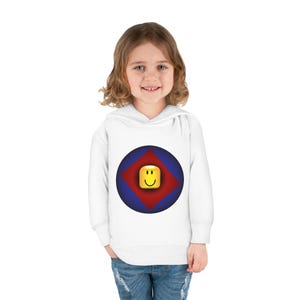 K&ouml;nnte beinhalten: Wei&szlig;er Kapuzenpullover mit einem blauen und roten Kreis-Motiv, das ein gelbes Smiley-Gesicht zeigt. Das Motiv ist eine stilisierte Darstellung einer beliebten Online-Gaming-Plattform.