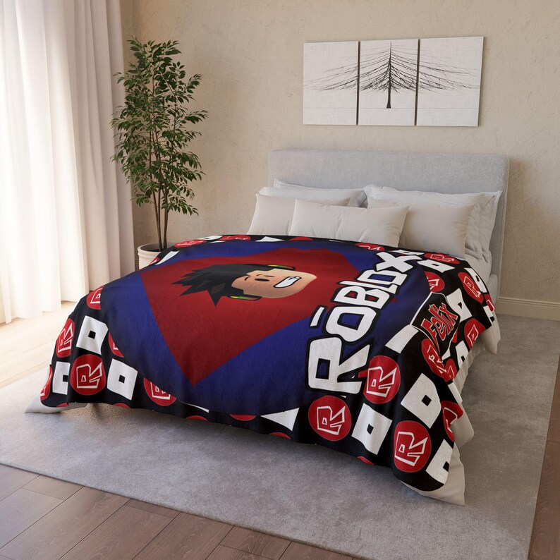 Peut inclure: Une couverture en polaire noire et rouge avec un logo Roblox et le visage d'un personnage Roblox au centre. La couverture a un motif r&eacute;p&eacute;titif du logo Roblox sur un fond noir.
