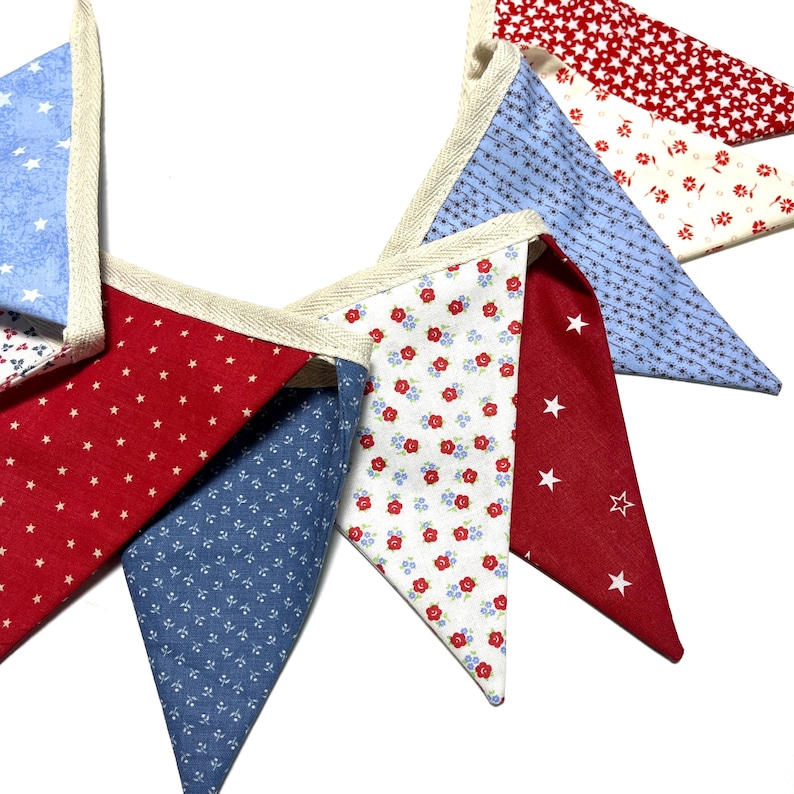Peut inclure: Guirlande d&eacute;corative compos&eacute;e de fanions triangulaires rouges, blancs et bleus. Les tissus pr&eacute;sentent des motifs d'&eacute;toiles et de fleurs. Les bords sont finis avec un biais cr&egrave;me, pour une ambiance festive.