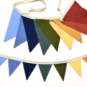 May include: A colorful fabric banner with alternating blue, navy, green, and yellow triangular flags. The banner is strung on a white cord.