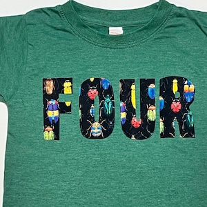 Pode incluir: Camiseta verde com a palavra "FOUR" impressa em preto. As letras são cobertas com um padrão de besouros coloridos.