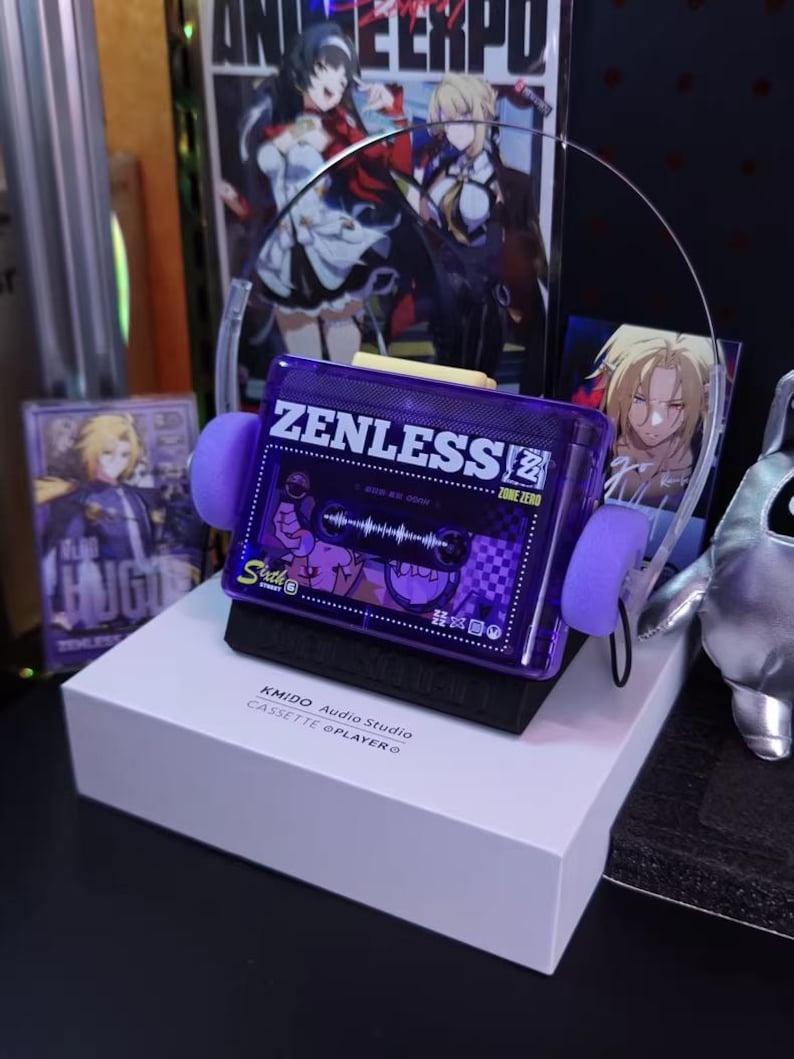 May include: A purple cassette tape player with the text "ZENLESS" and "ZONE ZERO" on the front. The player has purple ear pads and is sitting on a white box. The box has the text "KMIDO Audio Studio CASSETTE @PLAYER".