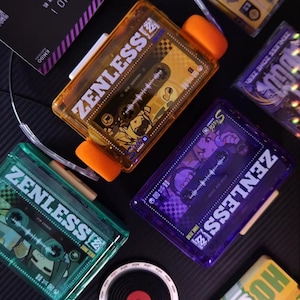 May include: A collection of colorful, transparent cassette tape-shaped containers with the text "ZENLESS" and "ZONE ZERO" printed on them. The containers are in shades of orange, green, and purple, with a black background.