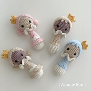 Peut inclure: Quatre hochets pour bébé en crochet en forme de personne portant une couronne. Les hochets sont en rose, bleu, beige et marron. Les hochets sont faits à la main et ont une surface texturée.