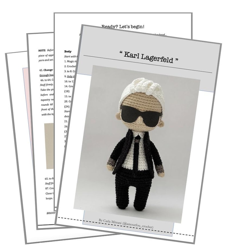 May include: A crochet amigurumi doll of Karl Lagerfeld, wearing a black suit, white shirt, black tie, and sunglasses. The doll is standing on a white background with the text "Karl Lagerfeld" above it.