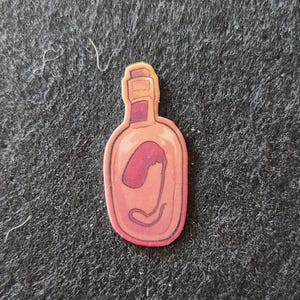 May include: A cartoon-style sticker of a bottle with a pink and red interior. The bottle has a light orange outline and a dark red stopper. The interior of the bottle has a red, kidney-shaped design.