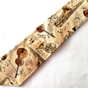 May include: A necktie with a light tan background featuring a repeating pattern of various musical instruments including saxophones, violins, and French horns, interspersed with black musical notes and staff lines across the entire fabric surface.