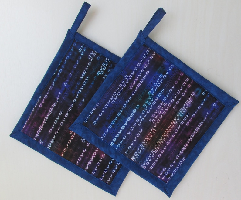 Puede incluir: Dos agarraderas cuadradas con borde azul y un patr&oacute;n de c&oacute;digo digital en tonos azules, morados y blancos. Cada agarradera tiene un lazo para colgar.