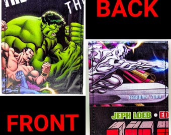 May include: A black wallet with a comic book cover featuring the Hulk and the Silver Surfer. The front of the wallet has the text "The Defenders" and the back has the text "Jeph Loeb - Ed Brubaker - February 2009".