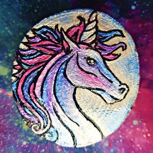May include: A hand-painted wooden unicorn head with a silver background. The unicorn has a pink and blue mane and horn. The background is a galaxy-like pattern.