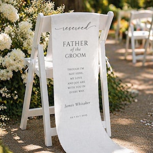 May include: A white wooden chair with a linen banner that reads "reserved" at the top. The banner says "FATHER of the GROOM" and includes a personalized message and date. The chair is set up outdoors for a wedding.