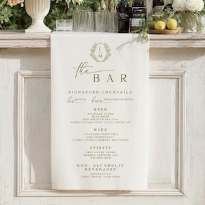 Wedding bar sign printed on ivory linen fabric, hanging on rustic wooden bar with greenery and florals