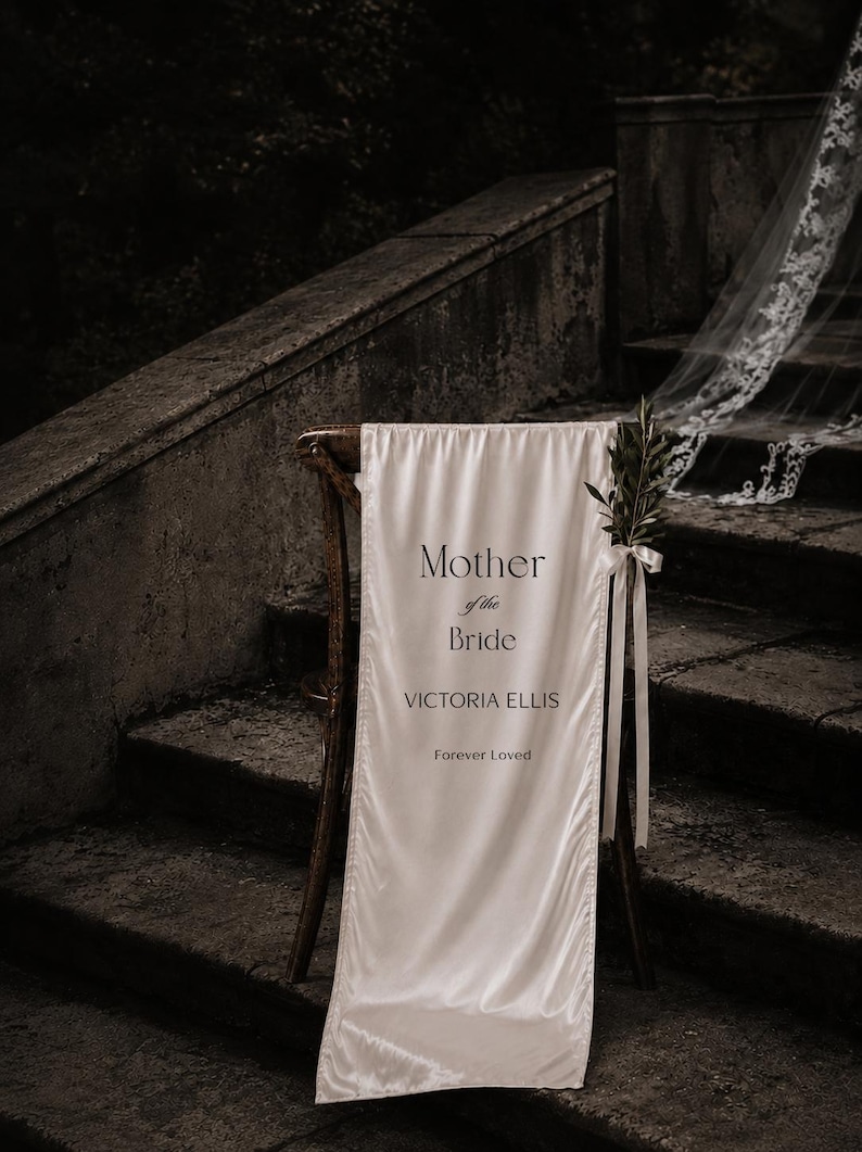 Personalized Mother of the Bride memorial fabric sign displayed on elegant wedding chair near ceremony staircase