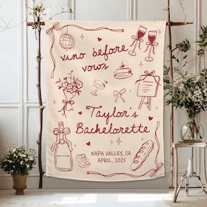 Op de afbeelding: Een cr&egrave;mekleurige stoffen banner met donkerrode lijntekeningen van een discobal, champagneglazen, een taart, een boeket, een menukaart, een fles en een ringdoosje. De tekst luidt: vino before vows, Taylor's Bachelorette, NAPA VALLEY, CA, APRIL, 2025.
