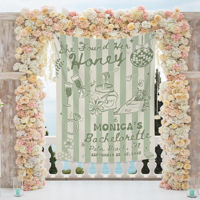 May include: A light green and white striped banner with the text "She Found Her Honey" and "Monica's Bachelorette Palm Beach, Fl September 25-27, 2025". The banner features illustrations of champagne glasses, a ring, and a jar of honey. The banner is surrounded by a floral arch.