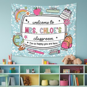 May include: A blue and white classroom tapestry with a welcome sign that says "Welcome to Mrs. Chloe's Classroom." The sign is surrounded by colorful illustrations of school supplies, stars, and the words "Friendly", "Kind", "Strong", "Enough", "Loved", "Brave", "Creative", "Worthy".