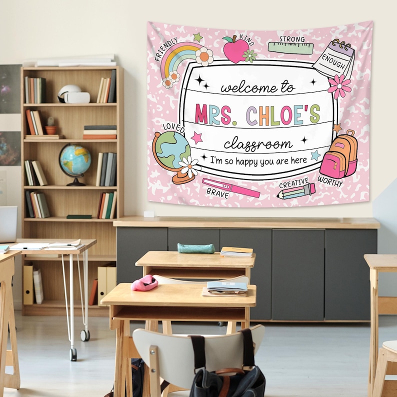 May include: A pink and white classroom tapestry with the text "welcome to MRS. CHLOE'S classroom" and the words "FRIENDLY", "LOVED", "KIND", "STRONG", "ENOUGH", "BRAVE", "CREATIVE", and "WORTHY" around the border.