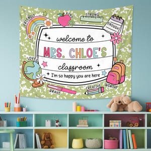 May include: A green and white tapestry with a welcome to Mrs. Chloe's classroom sign. The sign is surrounded by colorful illustrations of school supplies, stars, and words like 'friendly', 'kind', 'strong', 'enough', 'loved', 'brave', 'creative', and 'worthy'.