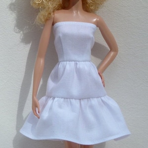 May include: A white strapless dress with a tiered skirt. The dress is made of a soft, lightweight fabric and has a simple, elegant design.