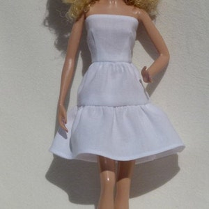 May include: A white strapless dress with a tiered skirt. The dress is made of a soft, flowing fabric.