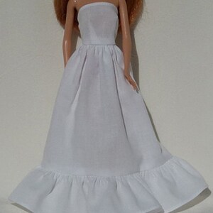 Op de afbeelding: Een witte strapless slip met een geruite zoom. De slip is gemaakt van een zachte, lichtgewicht stof en is perfect om te dragen onder jurken of rokken.