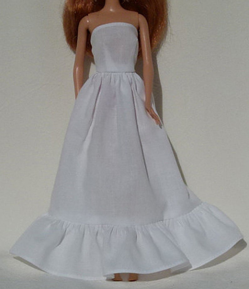 Op de afbeelding: Een witte strapless slip met een geruite zoom. De slip is gemaakt van een zachte, lichtgewicht stof en is perfect om te dragen onder jurken of rokken.