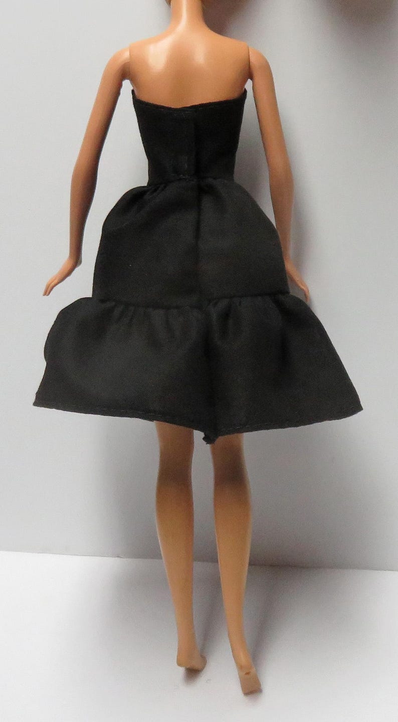 May include: A black strapless dress with a tiered skirt. The dress is made of a smooth fabric and has a simple design.