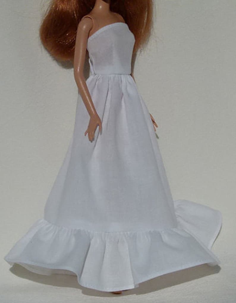 Op de afbeelding: Een witte strapless jurk met een geruite zoom. De jurk is gemaakt van een lichtgewicht stof en heeft een eenvoudig, elegant ontwerp.