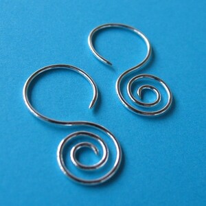 May include: A pair of silver earrings with a spiral design. The earrings are made of a thin wire and have a simple, elegant look.