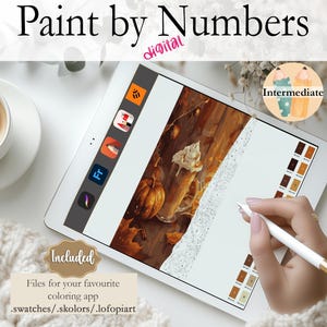 May include: Digital paint by numbers image on a tablet screen. The image is of a fall scene with a pumpkin, a cup of coffee, and a lace doily. The tablet is on a white surface with a cup of coffee and a white blanket.