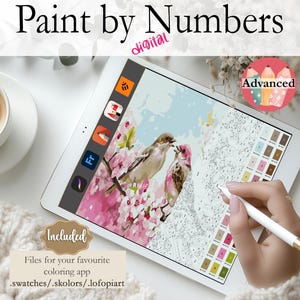 May include: A digital paint by numbers image on a tablet screen. The image features two birds perched on a branch with pink blossoms. The tablet is on a white surface with a cup of coffee and a white knitted blanket.