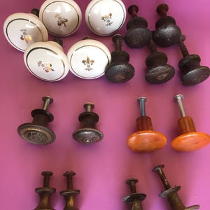 May include: A white ceramic mug with a black handle and the text "But First, Coffee" in a black, handwritten-style font. The mug is on a white surface.