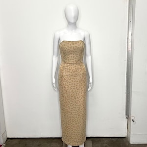 Puede incluir: Un vestido maxi sin tirantes con estampado de leopardo en tonos beige y marrón.