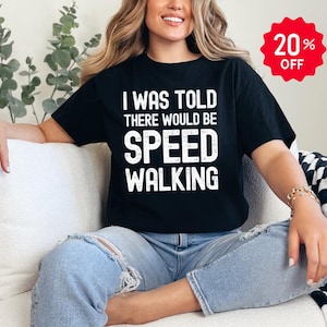 May include: A black short-sleeved t-shirt featuring the white distressed text I WAS TOLD THERE WOULD BE SPEED WALKING printed on the front. The shirt has a crew neckline and a standard fit, providing a casual look for everyday wear.