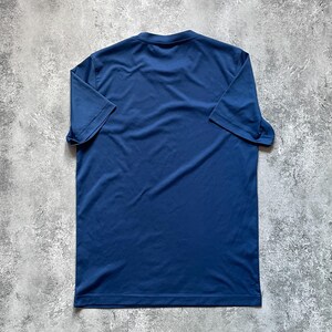 May include: A navy blue short-sleeved t-shirt. The shirt is made of a smooth, lightweight fabric and features a classic crew neck design. The shirt is laid flat, showcasing its simple, versatile style.