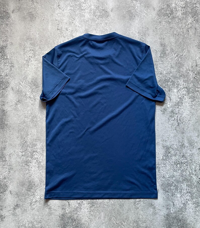 May include: A navy blue short-sleeved t-shirt. The shirt is made of a smooth, lightweight fabric and features a classic crew neck design. The shirt is laid flat, showcasing its simple, versatile style.