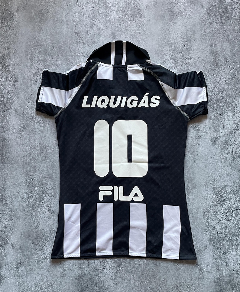 Puede incluir: Camiseta Liquigas en blanco y negro con el n&uacute;mero 10 y el logo de Fila. La camiseta tiene rayas blancas en las mangas y en la parte inferior, y la palabra "Liquigas" est&aacute; impresa en la parte superior de la espalda.