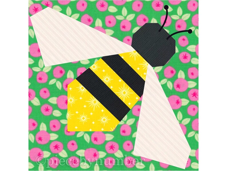 Square quilt block design of a stylized honey bee with embroidered antennae. Bee is yellow and black striped, with cream wings. Background is pink and green floral.