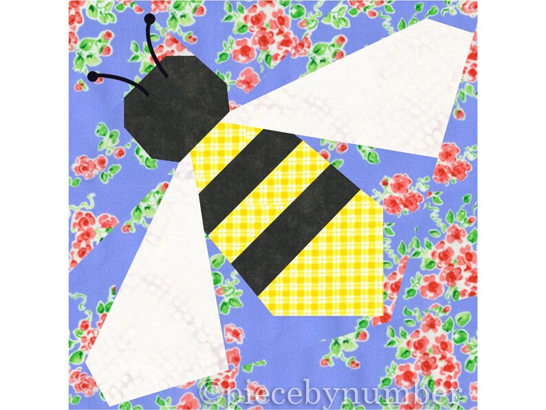 Square quilt block design of a stylized honey bee with embroidered antennae. Bee is yellow and black striped, with white wings. Background is blue and pink floral.