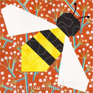 Square quilt block design of a stylized honey bee with embroidered antennae. Bee is yellow and black striped, with cream wings. Background is rust and teal stylized botanical print.