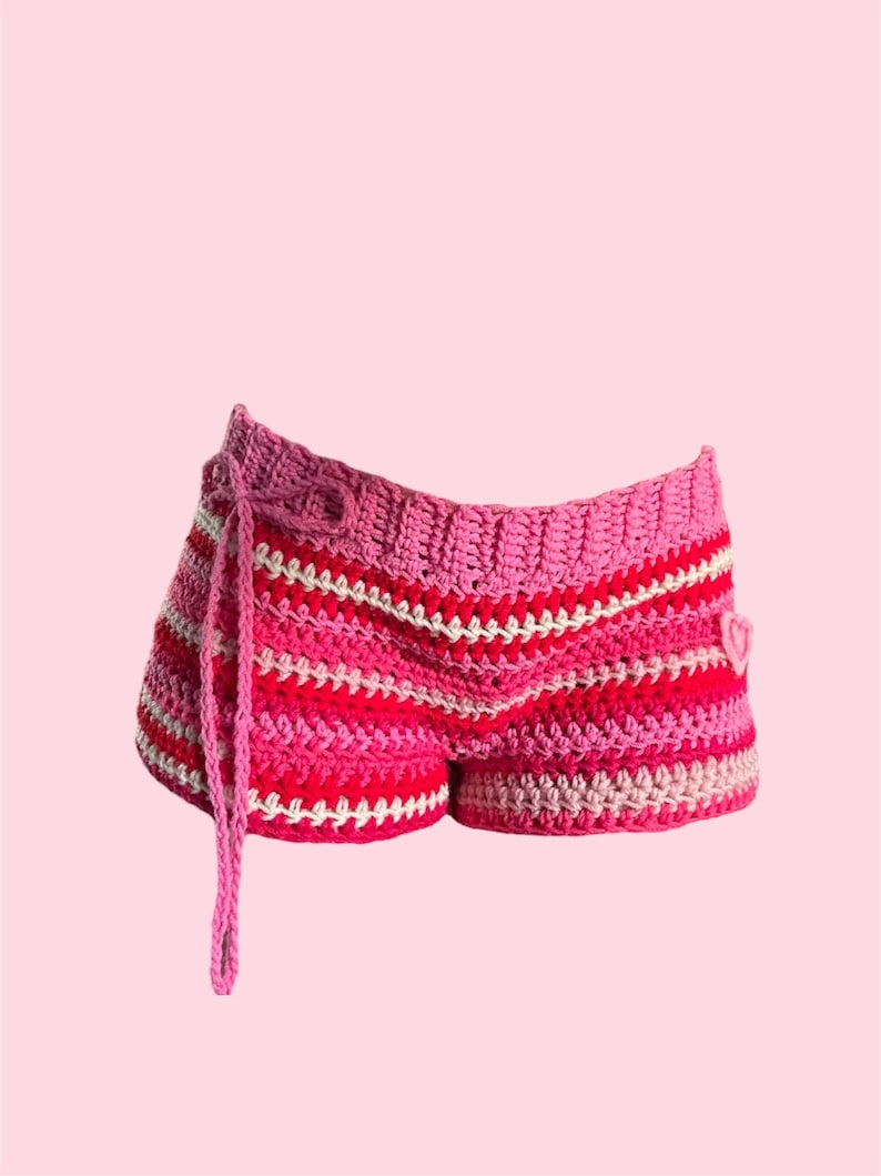 May include: Pink and white striped crochet shorts with a heart detail. The shorts have a tie at the waist.