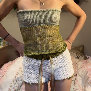 May include: A green and white crocheted tube top with a white crocheted skirt. The top is a halter style and the skirt is a high-waisted style.