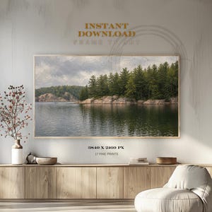 Peut inclure: Une impression encadrée d'un paysage avec un lac serein, une côte rocheuse et des arbres à feuilles persistantes. Le ciel est nuageux. L'impression est intitulée "INSTANT DOWNLOAD FRAME TV ART" et "3840 X 2160 PX 17 PINE PRINTS".